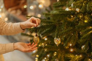 hands hanging ornaments on tree the reef apartments blog new holiday traditions