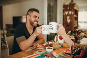 last-minute gift ideas blog couple cheersing coffee mugs at kitchen table the reef apartments blog